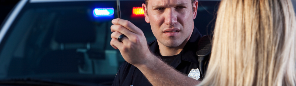 A police officer arresting a driver suspected of DUI and being over the legal limit at a roadside checkpoint.