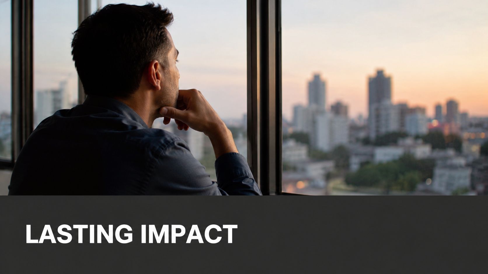 A pensive man looking out of a large office window at a city skyline during sunset.